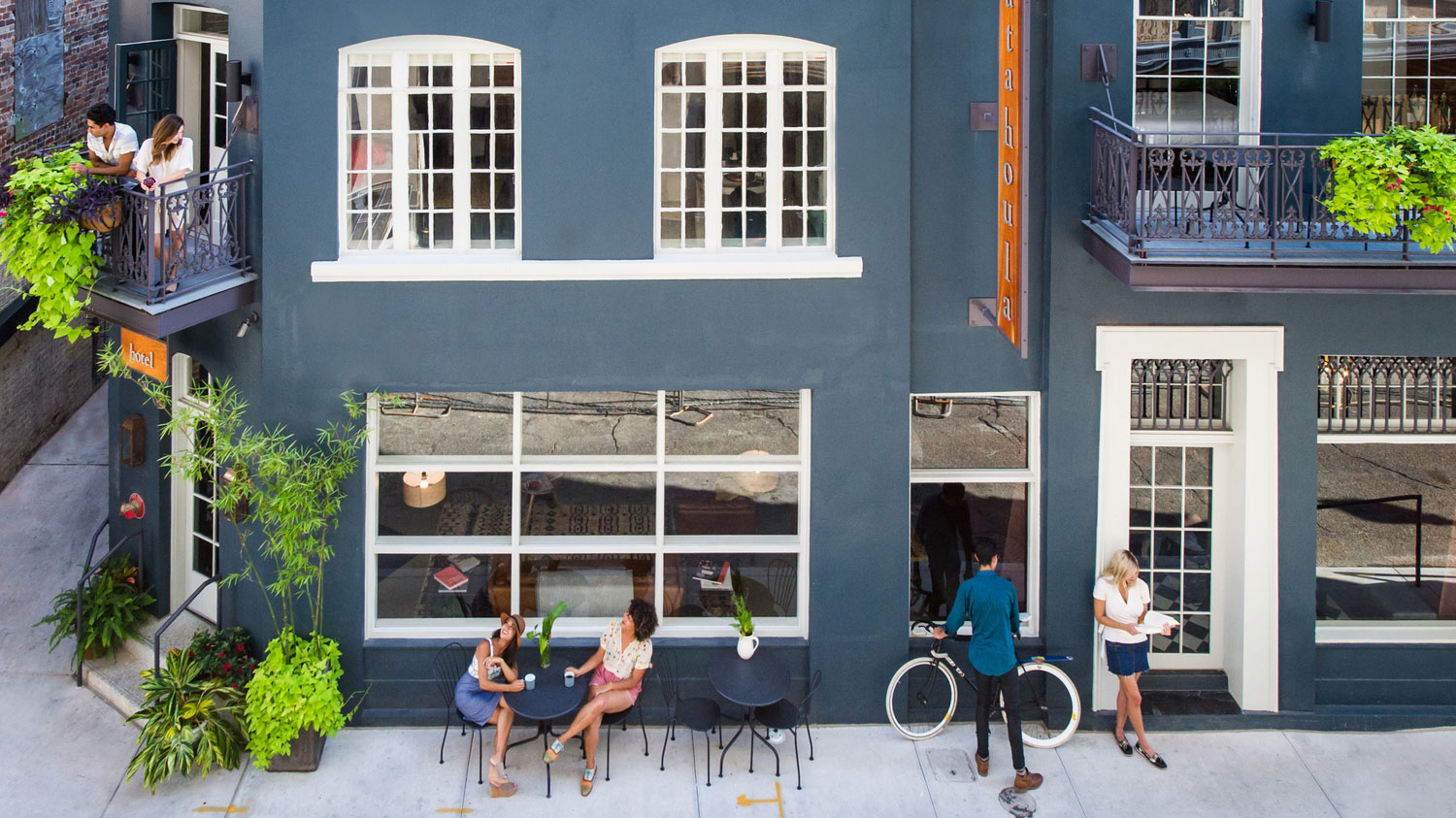 A blue building with white trim and people sitting outside